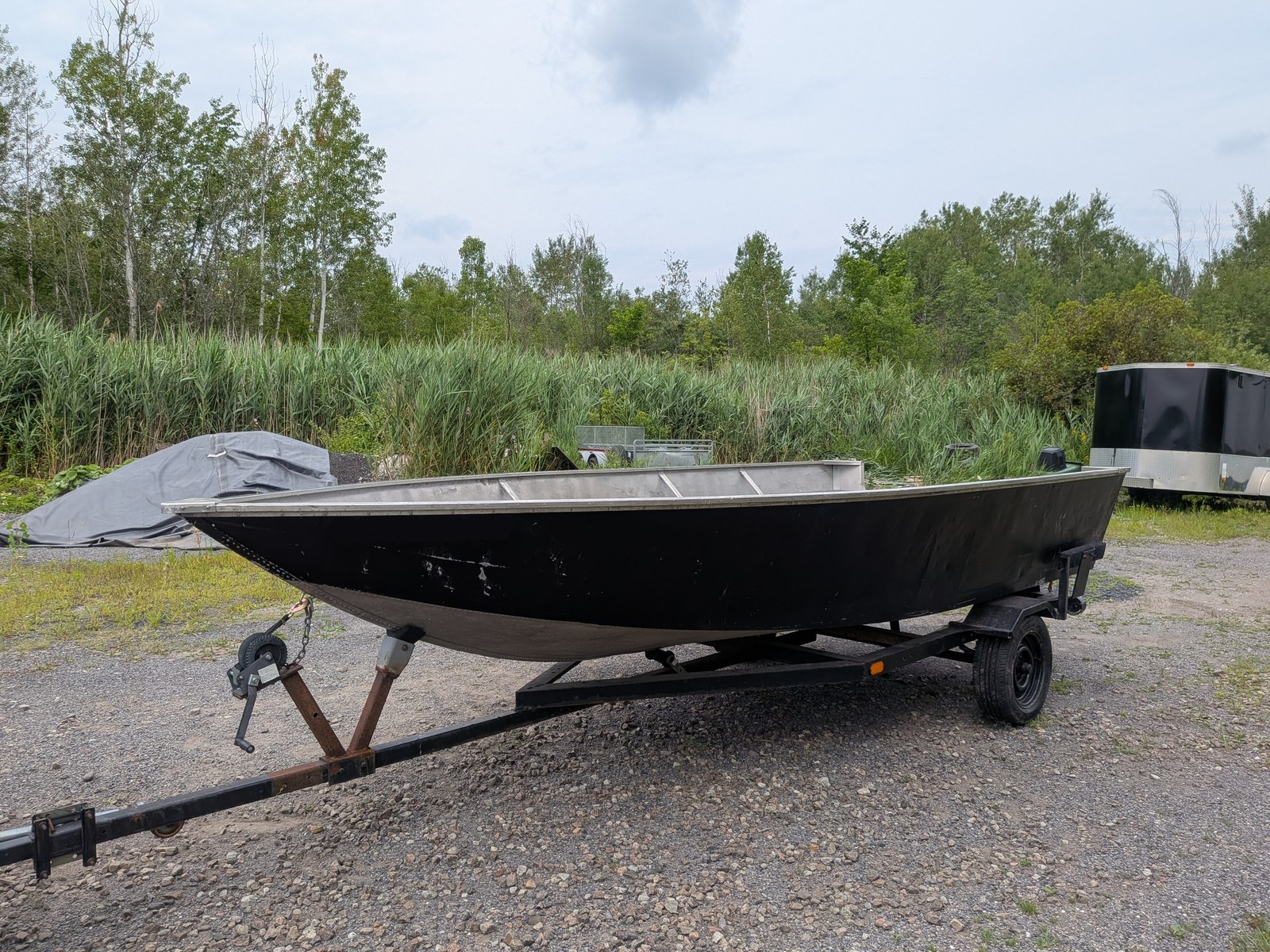 Le même bateau vu de l'autre bord, coque noire et plat-bord d'aluminium, l'intérieur encore complètement vide.