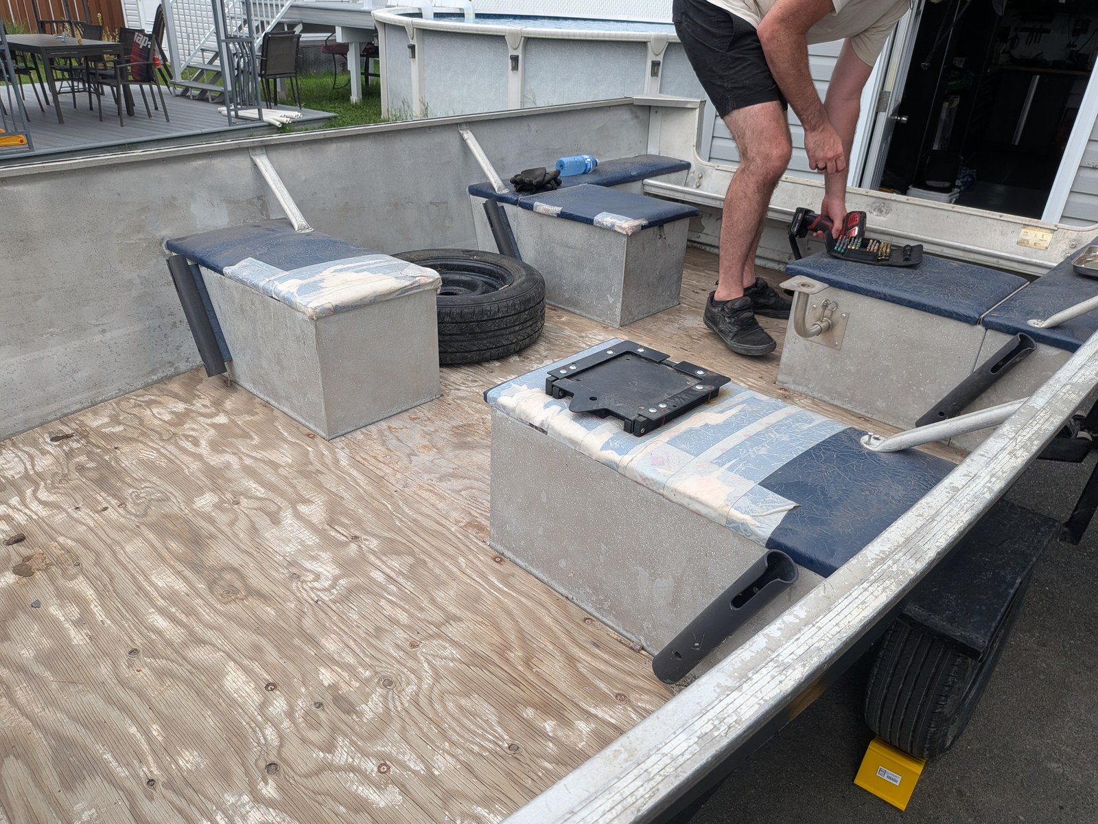 Le plancher de contreplaqué posé, les coffres de rangement en place, et une base de siège noire vissée sur l'un des coffres.