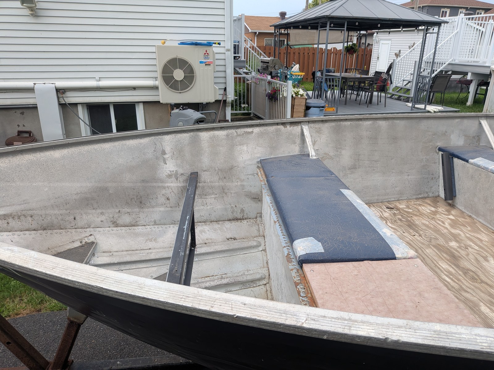 L'avant du bateau pendant la pose du plancher : contreplaqué neuf posé à côté du vieux coussin de banc bleu, parois d'aluminium encore nues.